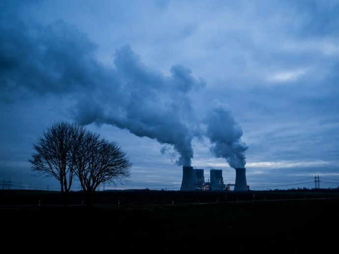 Cooling towers emitting steam under a cloudy sky